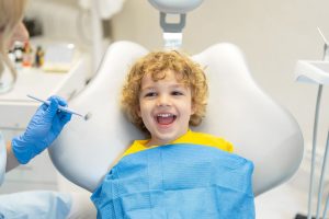 young child smiling on the dentist's bench