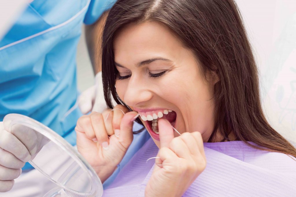 Female patient flossing her teeth in dental clinic
