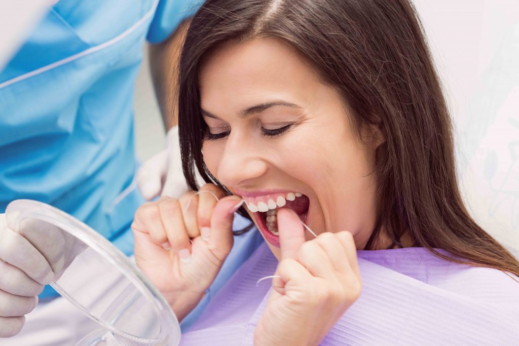 Patiente passant la soie dentaire ses dents dans une clinique dentaire