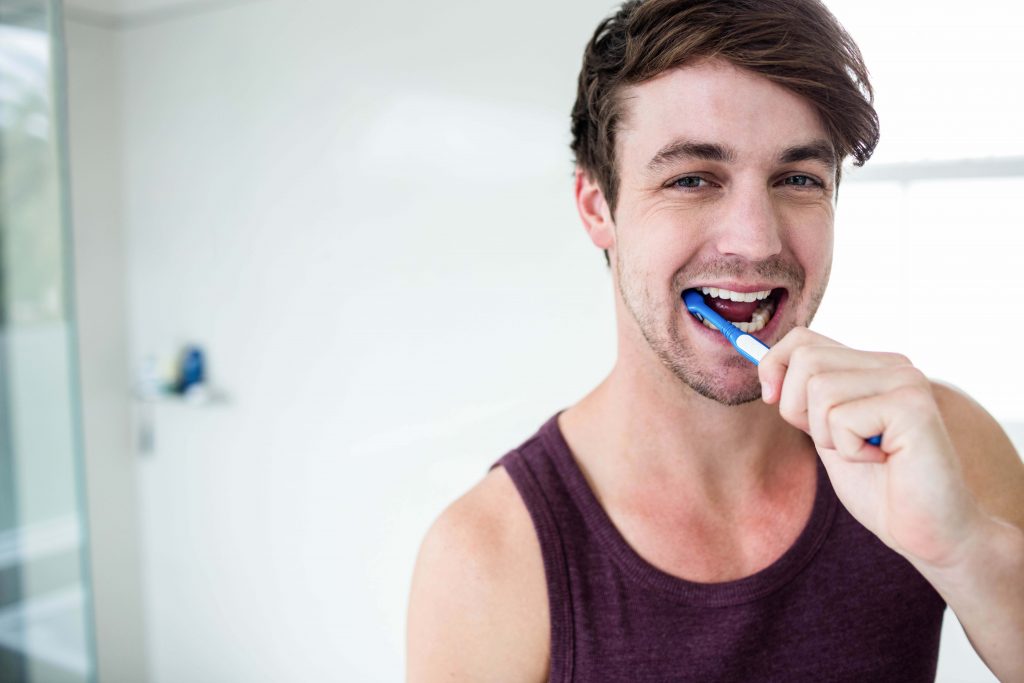 man brushing his teeth in bathroom