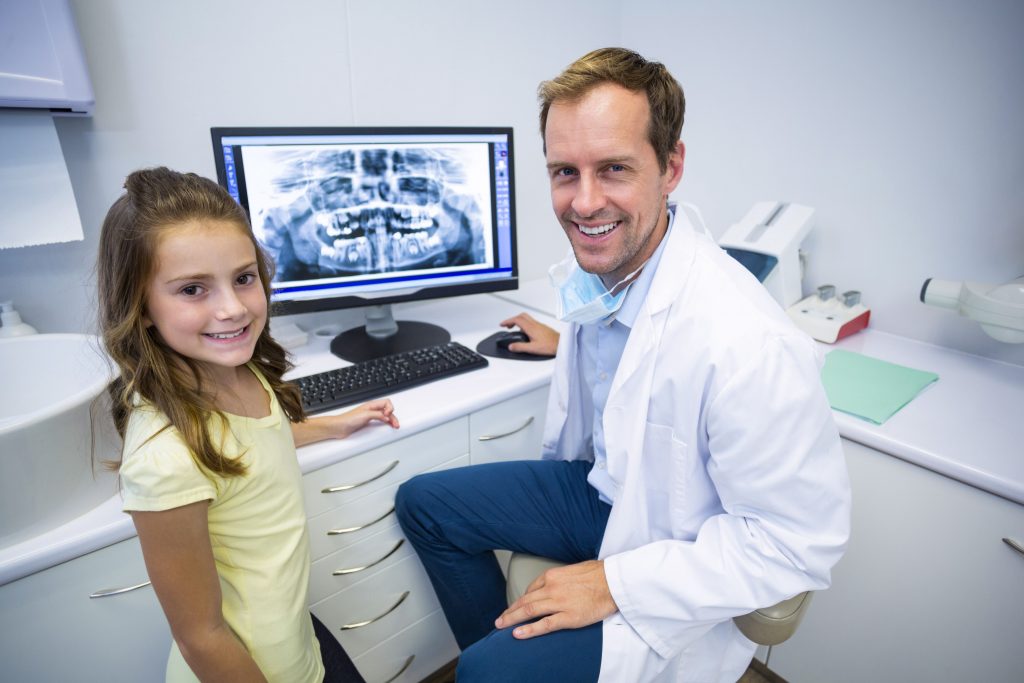 Portrait of smiling young patient and dentist in dental clinic