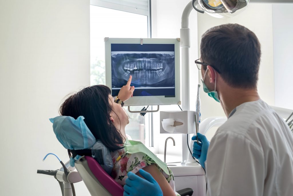 Dentist and patient looking at x-ray of teeth on screen