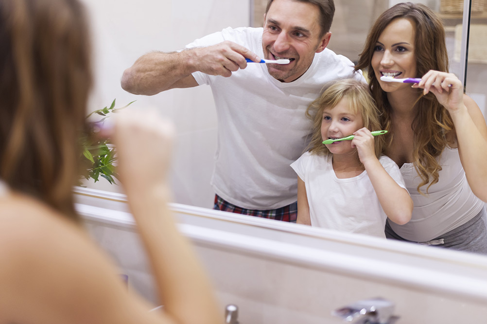 famille se brossant les dents devant le miroir