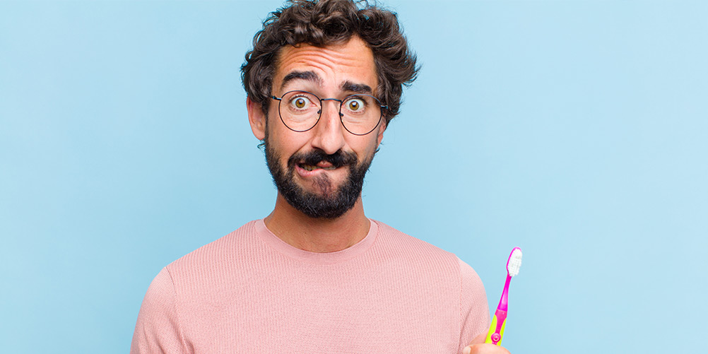 man looking indecisive about his toothbrush