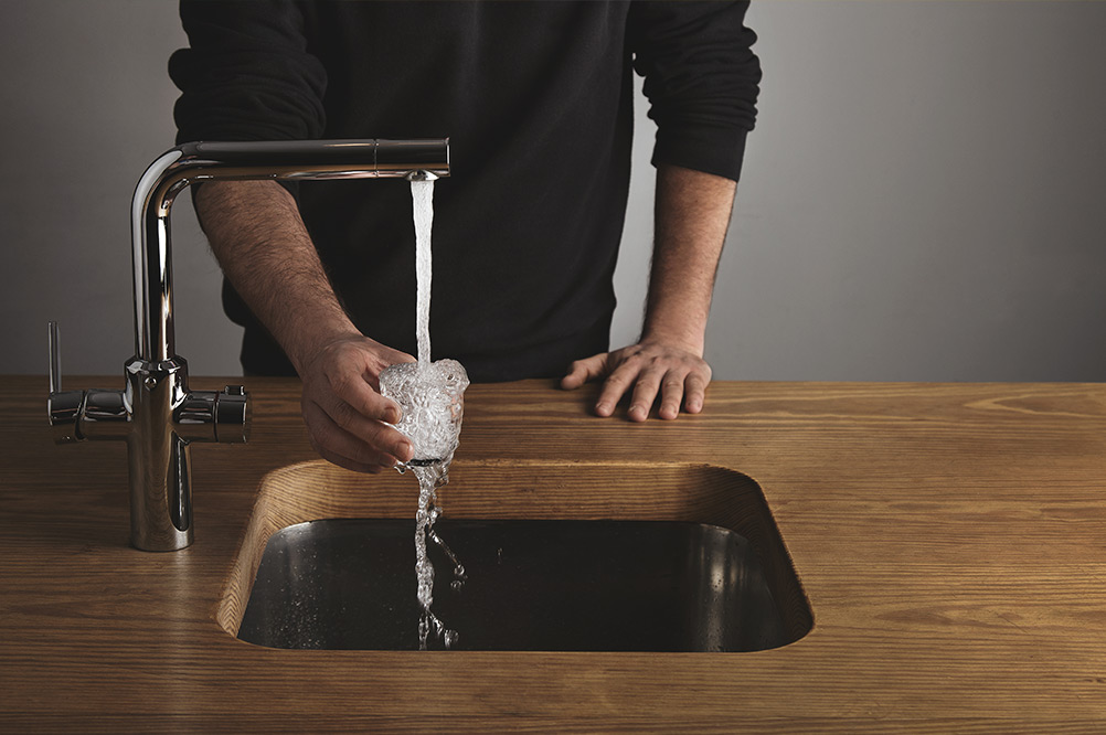 homme remplissant un verre d'eau dans un robinet