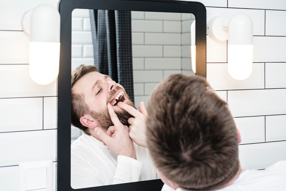 Homme qui regarde ses dents dans un miroir