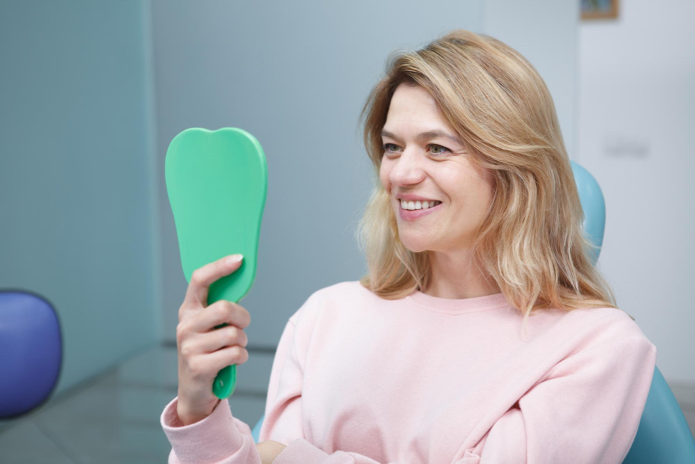 senior woman smiling looking at her white teeth in mirror