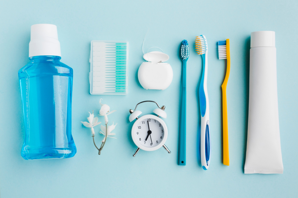 un kit de voyage dentaire vue de haut sur une table comprenant dentifrice, brosse, soie dentaire et rince-bouche
