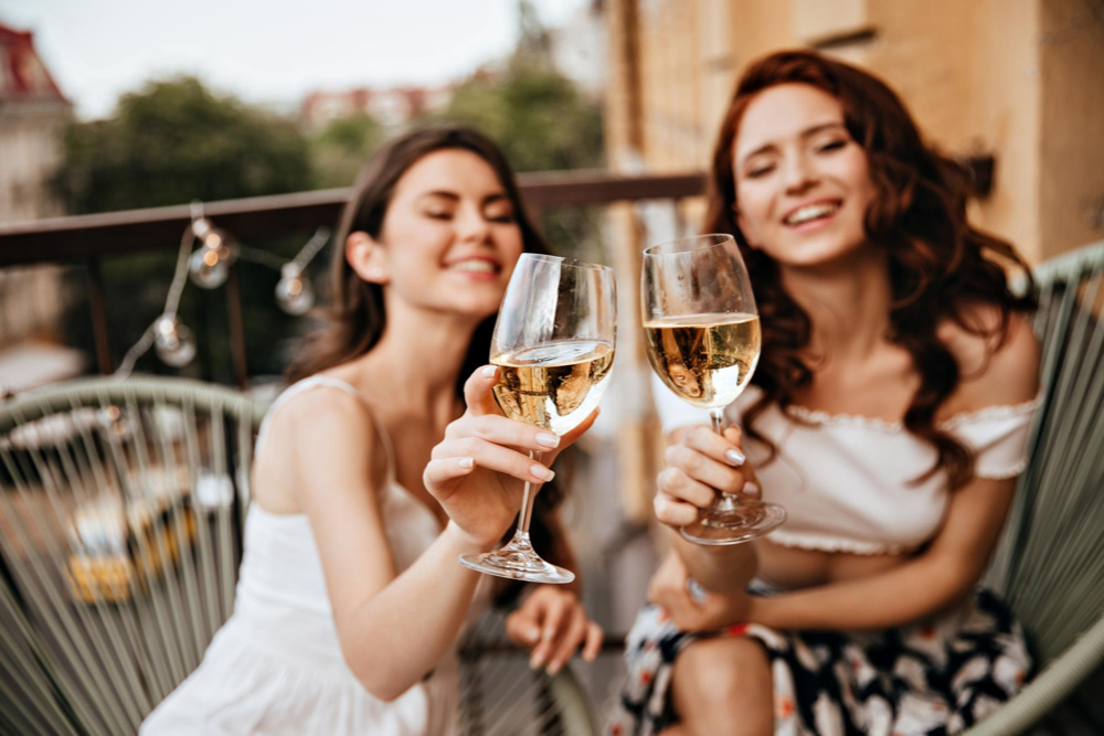 deux femmes avec verres de vin blanc ou rosé sur un balcon de la rive-sud de montréal