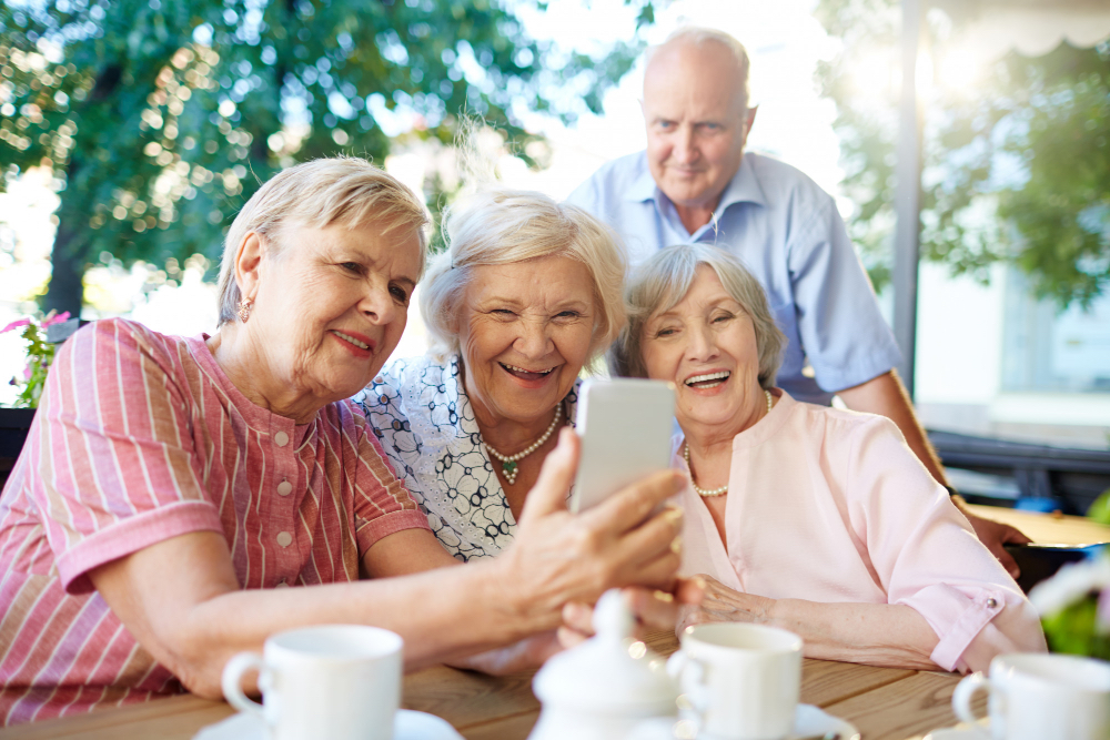 aînés souriants regardant un cellulaire ou prenant un selfie sur la rive sud