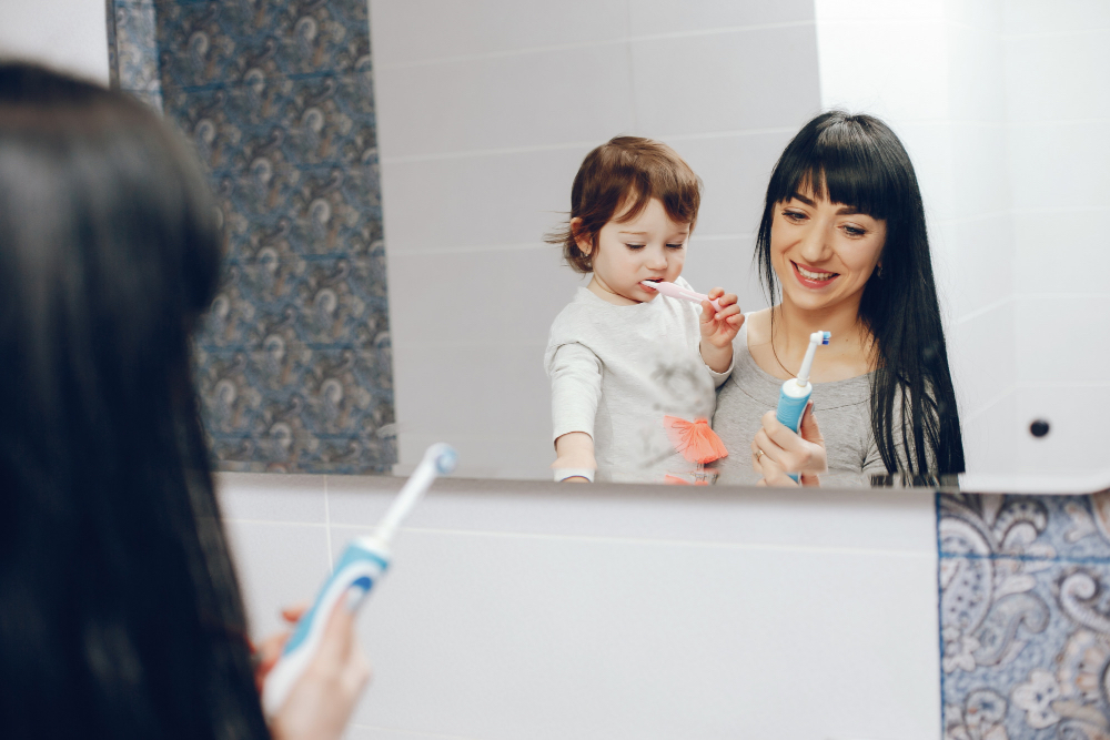 Photo d'une mère et sa fille qui se brosse les dents devant le mirroir.